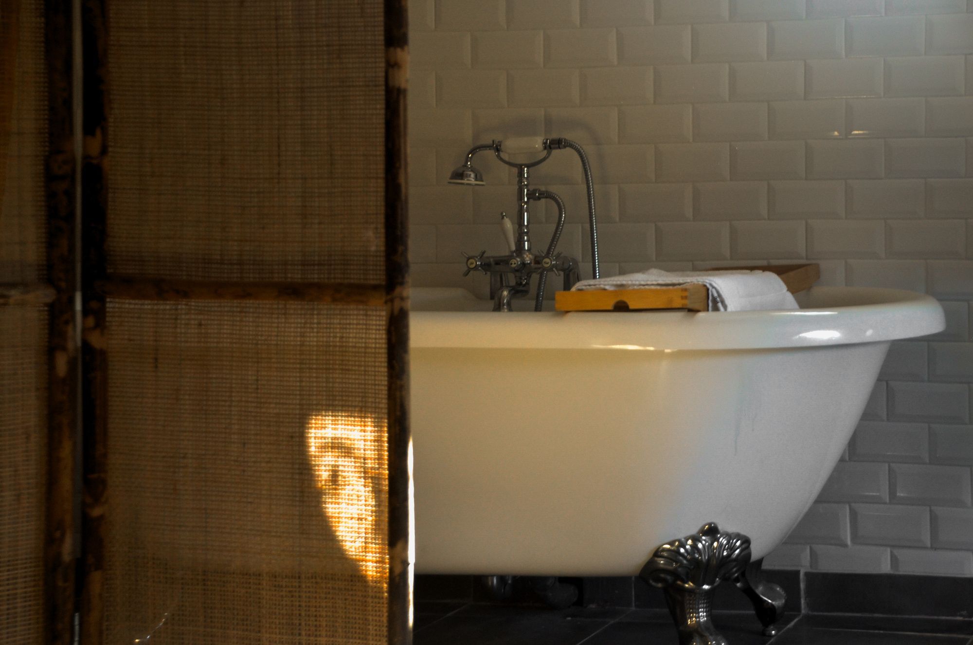 A roll-top bath against white tiles